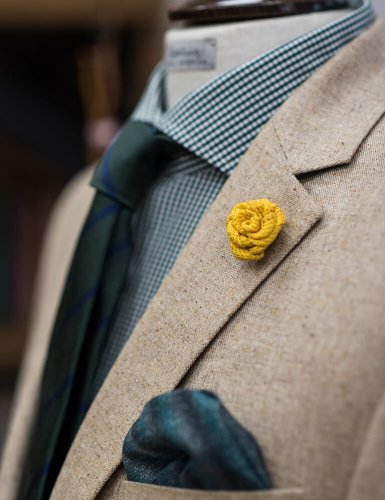 a men's jacket with a yellow flower brooch and a blue handkerchief