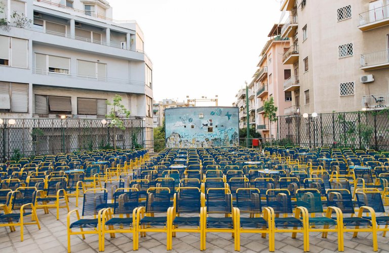 chairs and movie screen amidst apartment buildings.