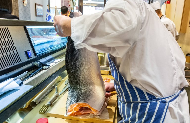 huge salmon being carved in a restaurant kitchen