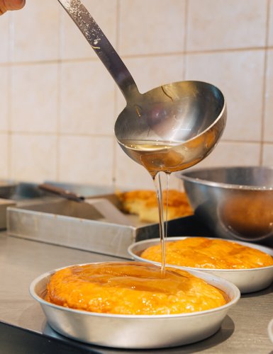 A ladle pouring syrup on galaktoboureko in a bakery in Athens. 