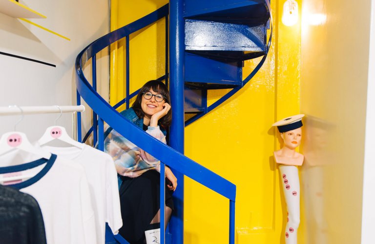 a smiling woman sitting on a yellow and blue staircase at Ode to Socks in Athens