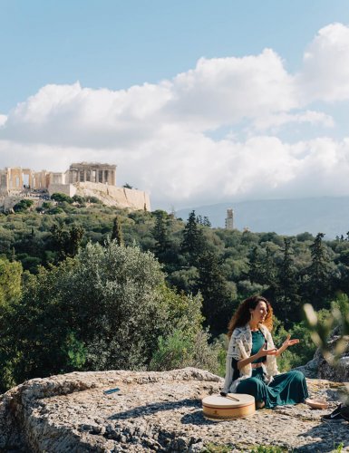 a woman sitting on a rock at Pnyx with a view of the Acropolis in Athens