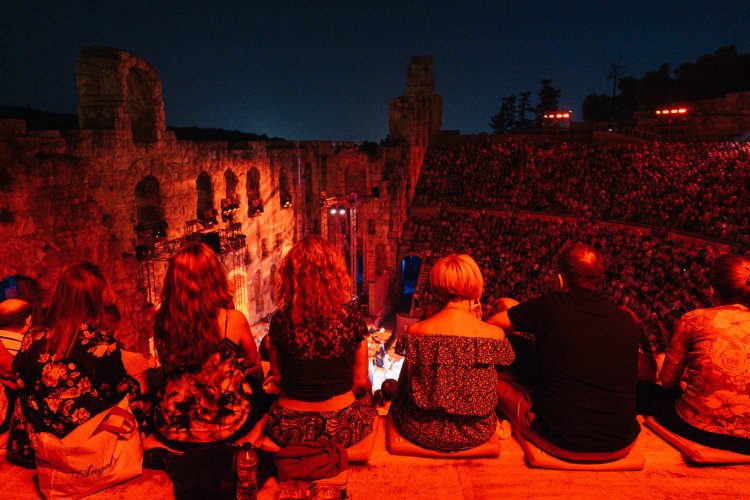 crowd gathered at the Odeon of Herodes Atticus in Athens for a concert at night, red lighting
