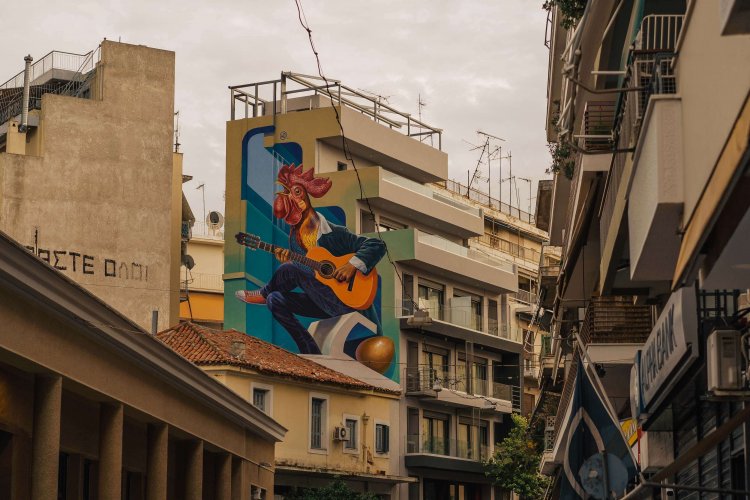 a colourful mural depicting a rooster wearing a suit and playing the guitar on a block of flats.