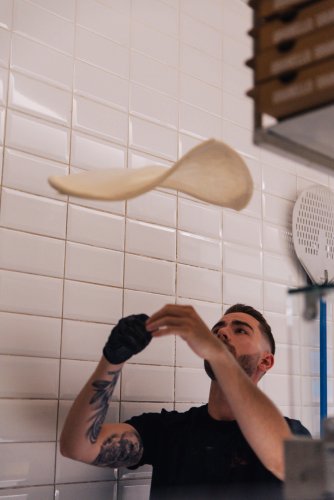 a man tossing the dough in the kitchen. 