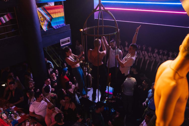 crowd in a nightclub, people dancing in stripper cage.