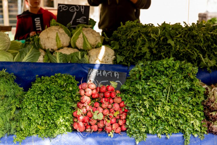 cauliflowers, herbs and radishes on a stall with price tags.