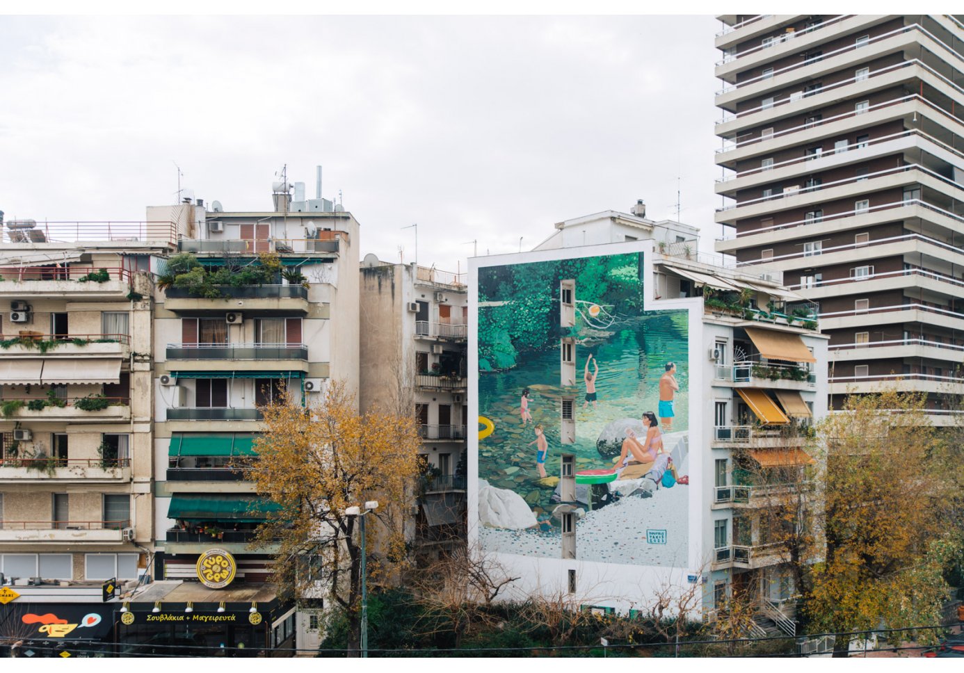 a green coloured mural on a building that depicts people on a riverside