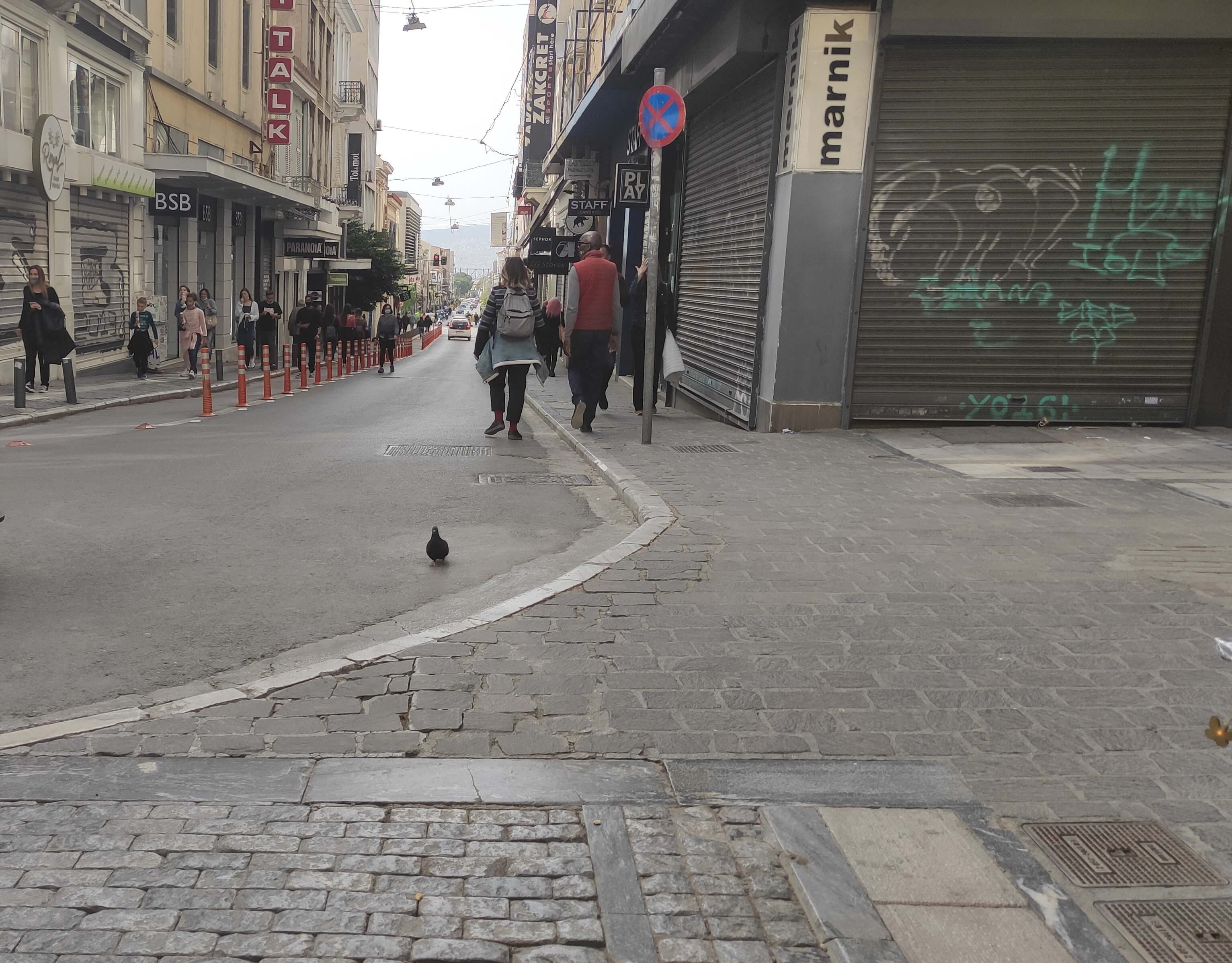 Returning to our initial itinerary, on Ermou Street, you will find that the pedestrian area ends at the junction with Aiolou Street. This is where we will choose the right pavement to continue our descent.  | Courtesy: Me Alla Matia 