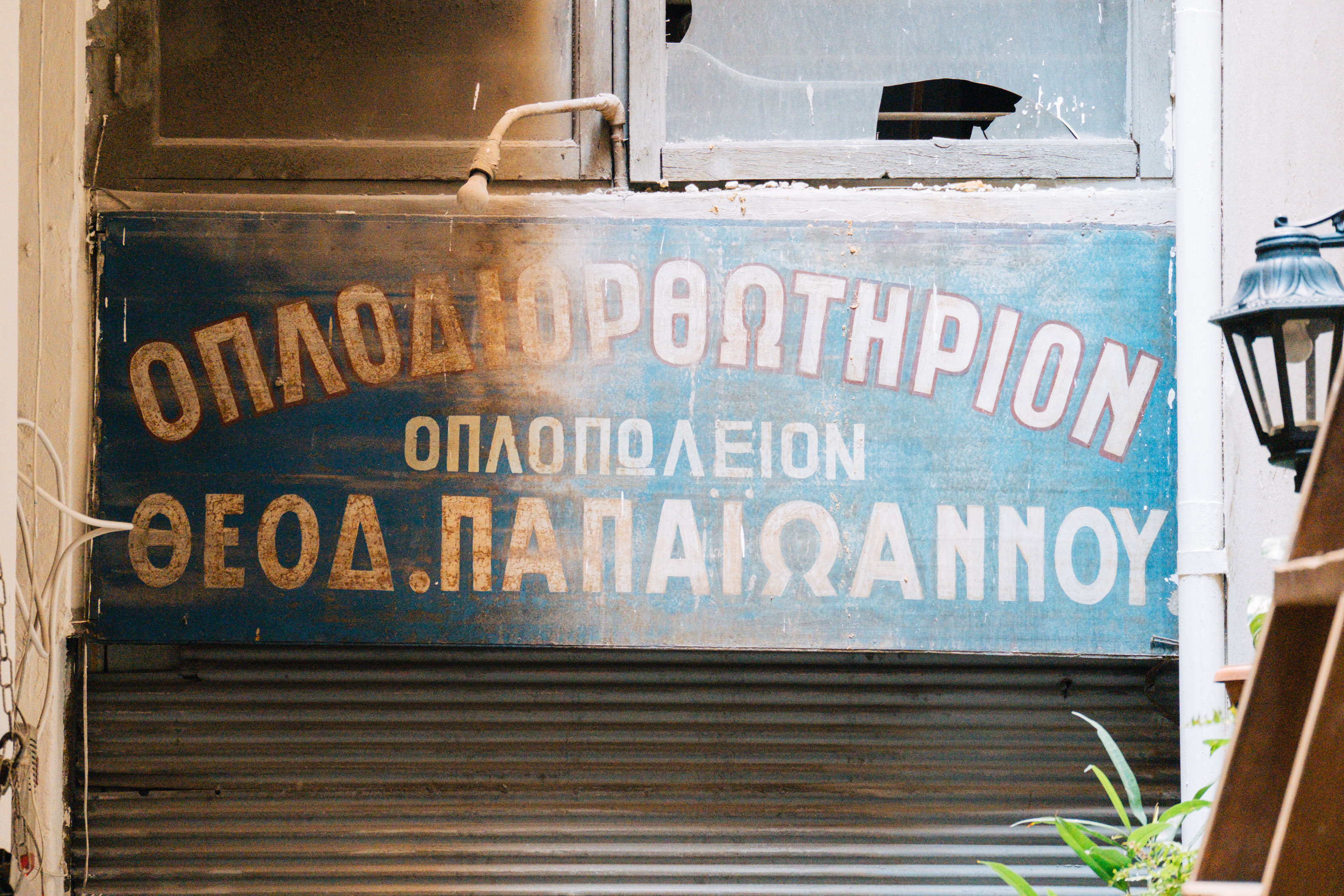 The legendary gun repair shop sign in Stoa Kairi. Spot the three different "Ω". | Photo: Georgios Makkas 