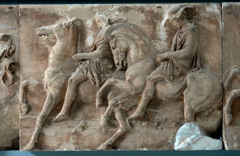 West frieze, Block IX. Two horsemen galloping sedately. The second wears a broad-brimmed hat (petasos). Examination of the folds of his tunic has revealed traces of green paint. | Courtesy: The Acropolis Museum. Photo by Sokratis Mavromatis.