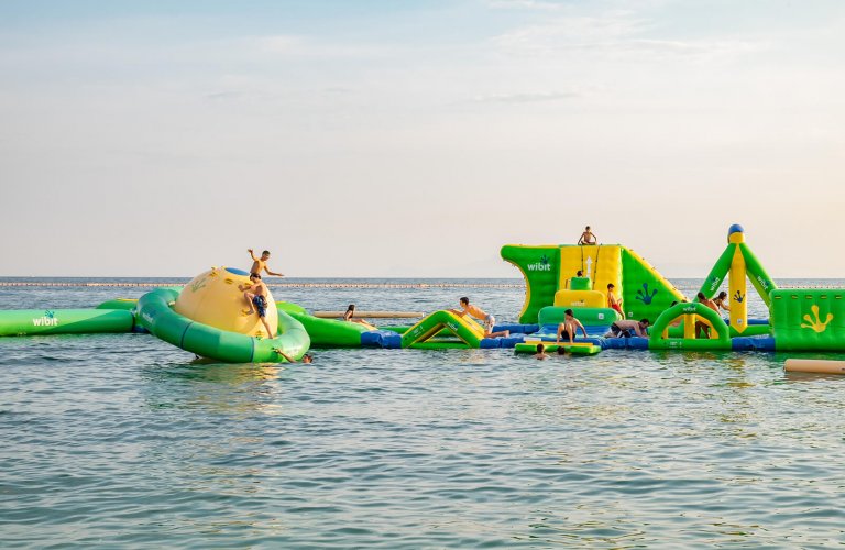 Children playing in the sea on a green and yellow floating playground