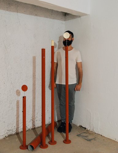 a man in a corner behind red metal tubes