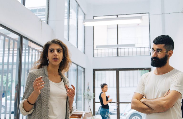 a man in a white tshirt watching a woman talk