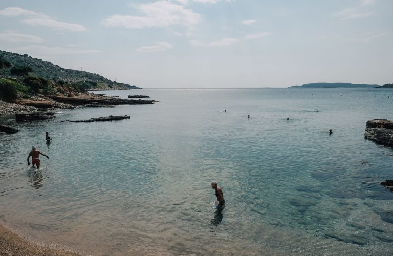 Three people in the sea on a beach. 