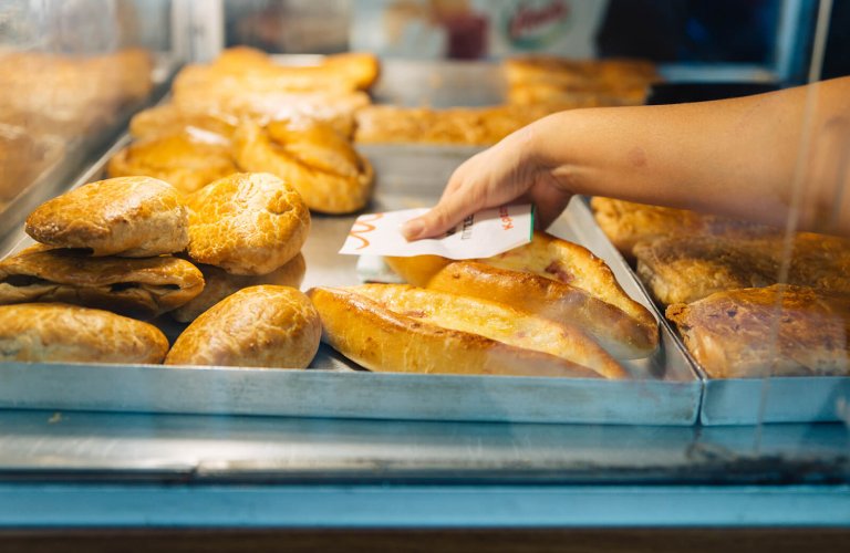 A hand taking out a pie from a tray at Mam pie shop in Athens. 