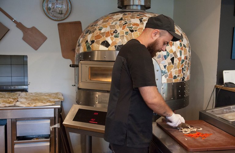 A man cutting up pizza toppings at Dal Professore. 