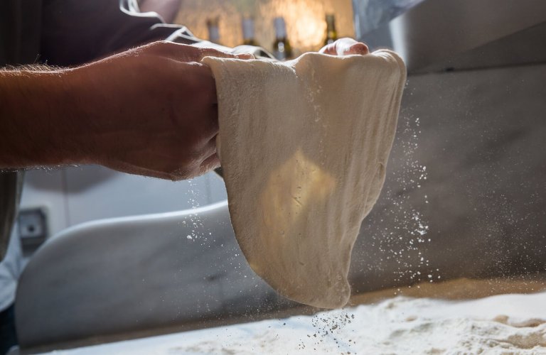 Hands holding pizza dough at Lollo's in Athens. 