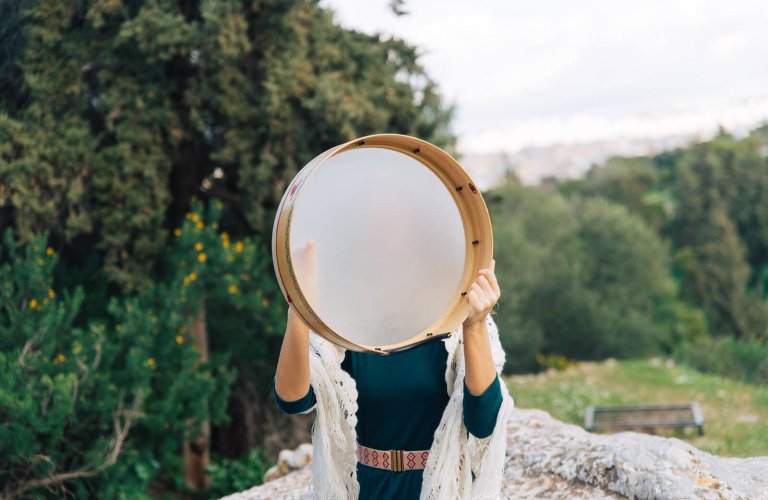 a woman holding a drum over her face in Pnyx Athens