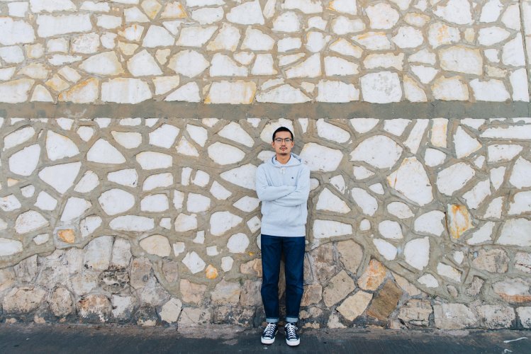 a man photographed against a stone wall