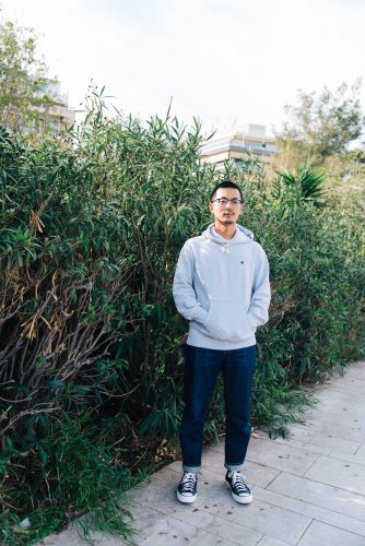 an Asian man photographed in front of plants in Athens