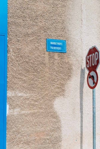 a wall sign that reads Polydefkous Street on a wall next to a stop sign