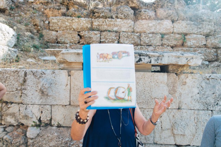 a woman tour provider with a dossier in front of her face showing in to a group of people