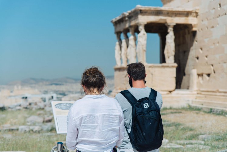 two people with a background view of the Caryatids atop the Acropolis Hill in Athens