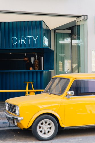 a yellow retro Mini Cooper in front of Dirty Mani in Athens