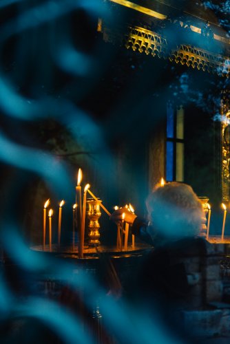 an old woman lighting a candle in a church, shot from behind