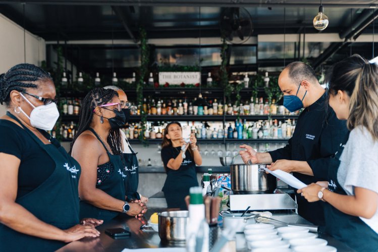 a group of people attending a cooking class, a woman taking a photo.