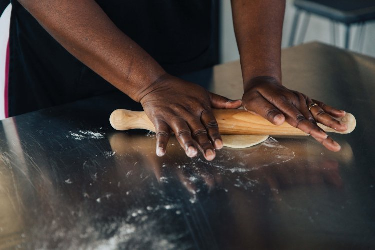 a woman using a rolling pin to strech the dough.