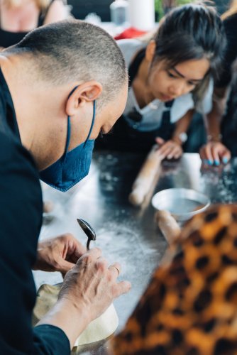 a chef working on a pie as a girl watches him as part of a cooking class