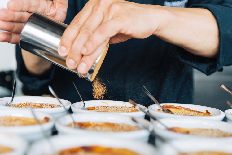 a chef's hands applying cinammon powder on dessers in bowls