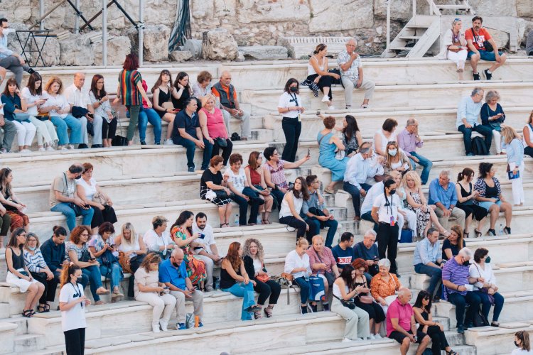 people sitting on the marble rows of the Odeon of Herodes Atticus in Athens