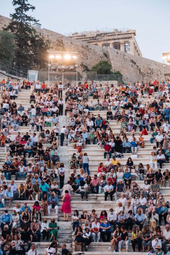 people sitting on the marble rows of the Odeon of Herodes Atticus in Athens