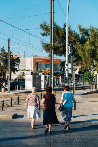 three elderly women crossing a road, urban setting.