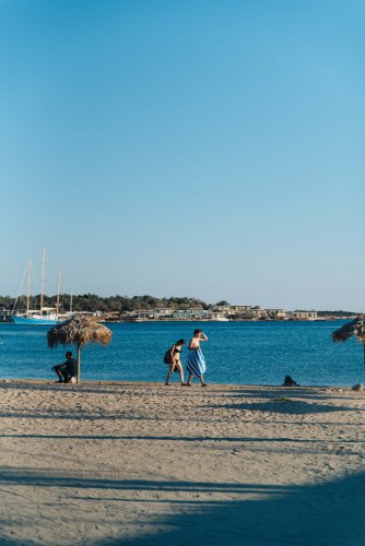 two people walking on the beach.