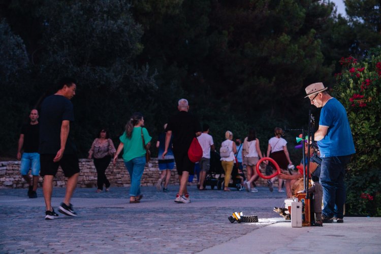 people walking down Areopagitou street and some street musicians.