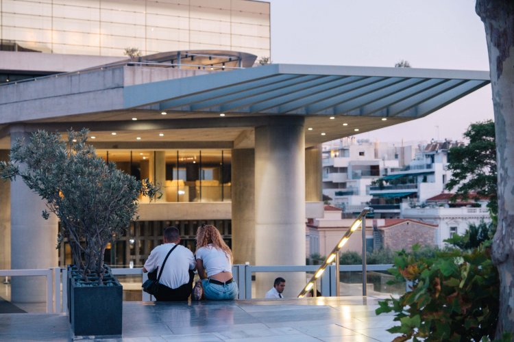 a couple sitting at the stairs of the Acropolis Museum.