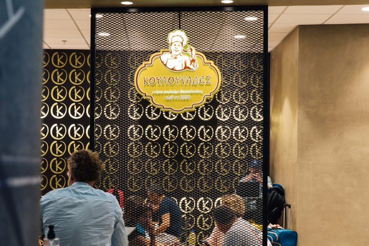 a yellow sign writing "koulourades", people eating and chatting.