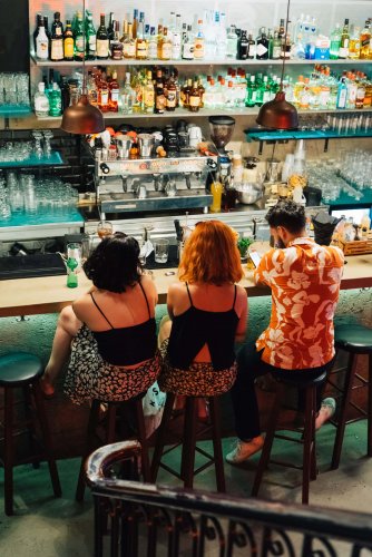 two girls and a boy sitting at the bar.