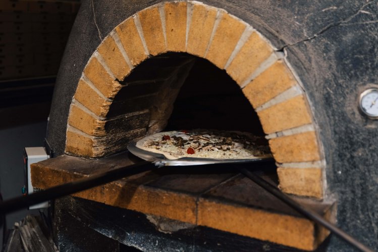 a pizza goes into the wood-fired oven.