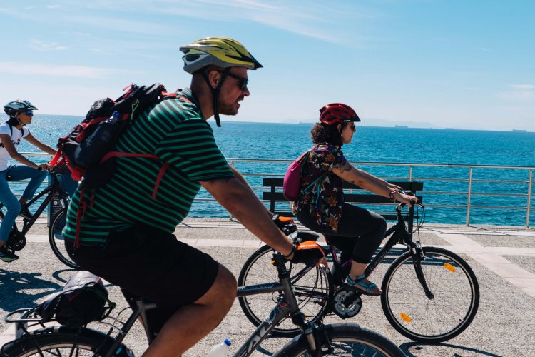 two women and a man riding their bikes at the seaside.
