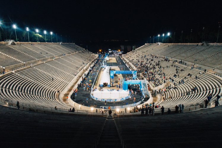 spectators and runners at the Panathenaic stadium during the night.