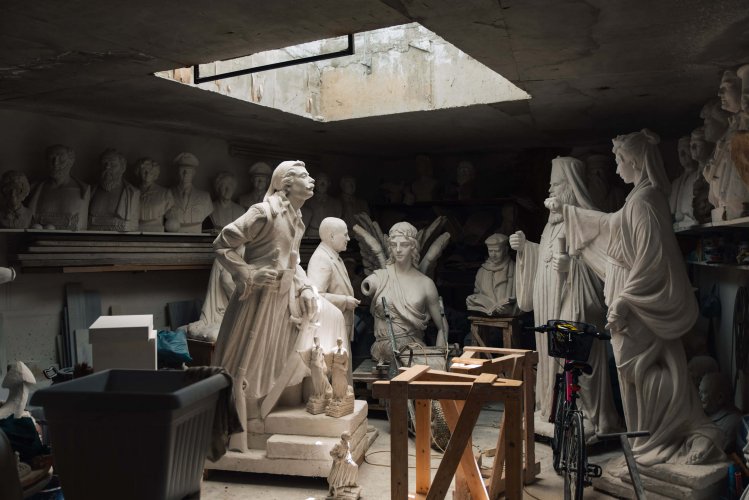 the inside of a sculpture studio, large statues and busts. 