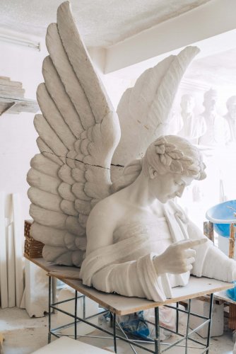 bust of a winged female figure on a table.