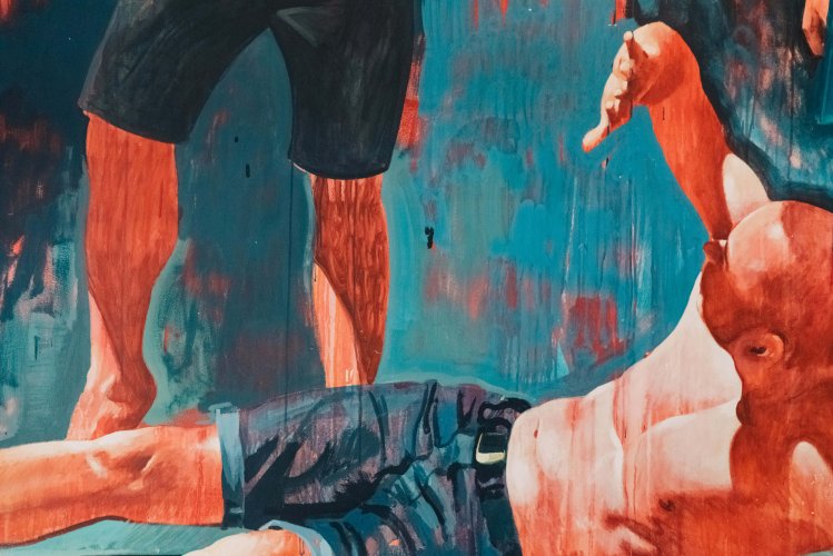 detail of a mural, a man on the ground covering his face with his hand, the legs of a man standing next to him.