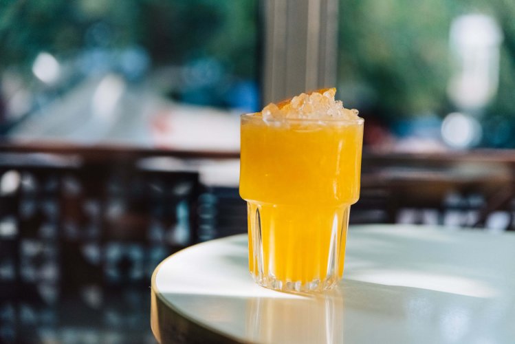 an orange juice glass on a marble table, rays of sunshine. 