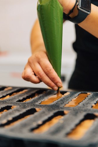 a pastry chef adding chocolate to a pastry mould.